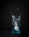 Ice falls into the glass. splash of frozen water. Blue beautiful wine glass