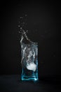 Ice falls into the glass. splash of frozen water. Blue beautiful wine glass