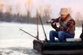 Ice fishing. Fisherman sitting on frozen lake and drink tea