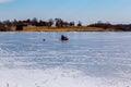 Ice fishing; frozen lake surface in winter with ice fisherman on the lake. Royalty Free Stock Photo