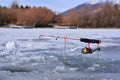 Ice fishing pole with pink real and pole sitting on ice waiting for fish