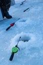 Ice fishing rod ready in a frozen river hole, waiting for fish bite, detail of a fisherman