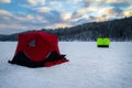 Ice fishing tent on a frozen lake at sunset. Fisherman camp on a peaceful winter evening Royalty Free Stock Photo