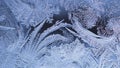 Ice and frost on window glass in winter. Pattern of frozen water crystals, similar to leaves of magic plants. Dark blue and white Royalty Free Stock Photo