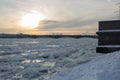 Ice on frozen Neva river, bridge, silhouettes of St. Petersburg buildings.