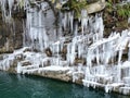 ice is hanging from the side of a rock ledge by the water Royalty Free Stock Photo