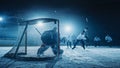 Ice Hockey Game in Rink Arena: Forward Player who Does Slapshot, Shoots Puck with Stick, Goalie Royalty Free Stock Photo