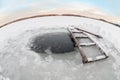 Ice hole for winter swimming with wooden stair and shovel. Wide angle view Royalty Free Stock Photo