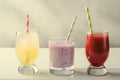 Ice lemonade, strawberry and berries smoothies with cocktail tubes in glasses, on white background.