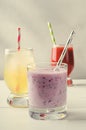 Ice lemonade, strawberry and berries smoothies with cocktail tubes in glasses, on white background.