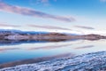 Ice on the shore of lake. Mountains and sky are reflected in the lake at sunset Royalty Free Stock Photo