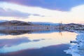 Ice on the shore of lake. Mountains and sky are reflected in the water Royalty Free Stock Photo