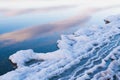 Ice on the shore of lake in winter. Clouds and sky are reflected in the water surface Royalty Free Stock Photo