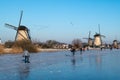 Ice skater on a frozen windmill canal at sunrise moment