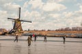 Ice skaters on a frozen windmill canal at sunrise moment