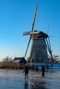 Ice skaters on a frozen windmill canal at sunrise moment Royalty Free Stock Photo
