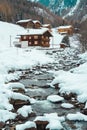 Ice and snow covered creek on a cold winter day infront of traditional wooden cabins of little mountain village Royalty Free Stock Photo