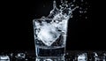Ice splashing into a glass of water on a black background, summer Royalty Free Stock Photo