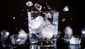 Ice splashing into a glass of water on a black background, summer Royalty Free Stock Photo