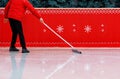 An ice stadium worker in a red jacket cleans the ice with a special rubberized ice mop. Copy space