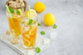 Ice tea with lemon, brown sugar, mint leaves and ice cubes in a glass on a board on a light background. Summer refreshing drink. Royalty Free Stock Photo