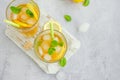 Ice tea with lemon, brown sugar, mint leaves and ice cubes in a glass on a board on a light background. Summer refreshing drink. Royalty Free Stock Photo