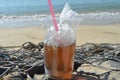 Ice tea in a plastic cup with red straw on stone. Beach refreshments Royalty Free Stock Photo