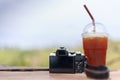 Ice tea in plastic glass and mirrorless camera on the wooden tab Royalty Free Stock Photo