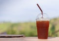 Ice tea in plastic glass on the wooden table mountain background Royalty Free Stock Photo