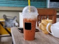 ice Thai milk tea with foam milk on the top in plastic glass. cutomer put it on the table. blur background Royalty Free Stock Photo