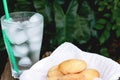 Ice and water in glass and ancient egg cakes in plate on wood stump on green leaf background