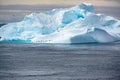 Huge iceberg, roosting place for penguins and cormorants. Blue and turquoise iceberg in Antarctica with many animals. Sharp photo