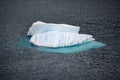 Iceberg shining in white, turquoise color and striped texture in dark blue riffled Southern Antarctic Ocean, Antarctica