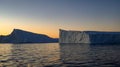 Iceberg of triangular shape with abrupt sides on a calm sea with a light of