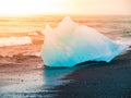 Icebergs sphashed by sea waves on black beach at sunrise time near Jokulsarlon glacier lake, Iceland