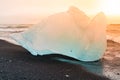 Icebergs sphashed by sea waves on black beach at sunrise time near Jokulsarlon glacier lake, Iceland