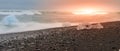 Icebergs sphashed by sea waves on black beach at sunrise time near Jokulsarlon glacier lake, Iceland