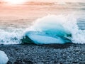 Icebergs sphashed by sea waves on black beach at sunrise time near Jokulsarlon glacier lake, Iceland