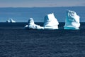 Icebergs in sunlight shining in turquoise over dark blue Arctic Ocean, Greenland