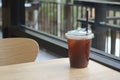 Iced black tasty coffee in plastic cup with straw on wooden table in coffee shop Royalty Free Stock Photo