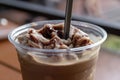 Iced blended coffee with milk in plastic glass on wooden table