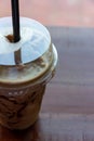 Iced blended coffee with milk in plastic glass on wooden table