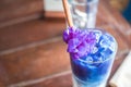 Iced Butterfly Pea Latte with milk on the wooden table.
