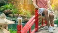 Iced cappuccino with straws placed on head of red wooden bridge with blurred image of couple sit on bridge railing and small
