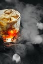 Iced caramel cocktail in a glass with syrup, ice and whipped cream. Black background and smoke