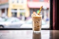 iced chai latte with a cream swirl, shot through caf window