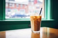 iced chai latte with a cream swirl, shot through caf window