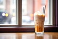 iced chai latte with a cream swirl, shot through caf window