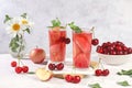 Iced cherry tea or cocktail with mint and lbd,recipe for refreshing summer drink.Glass with apple fruit lemonade on light concrete Royalty Free Stock Photo