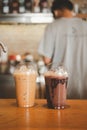 Iced chocolate and iced mocha on table with blurred back view of baretta